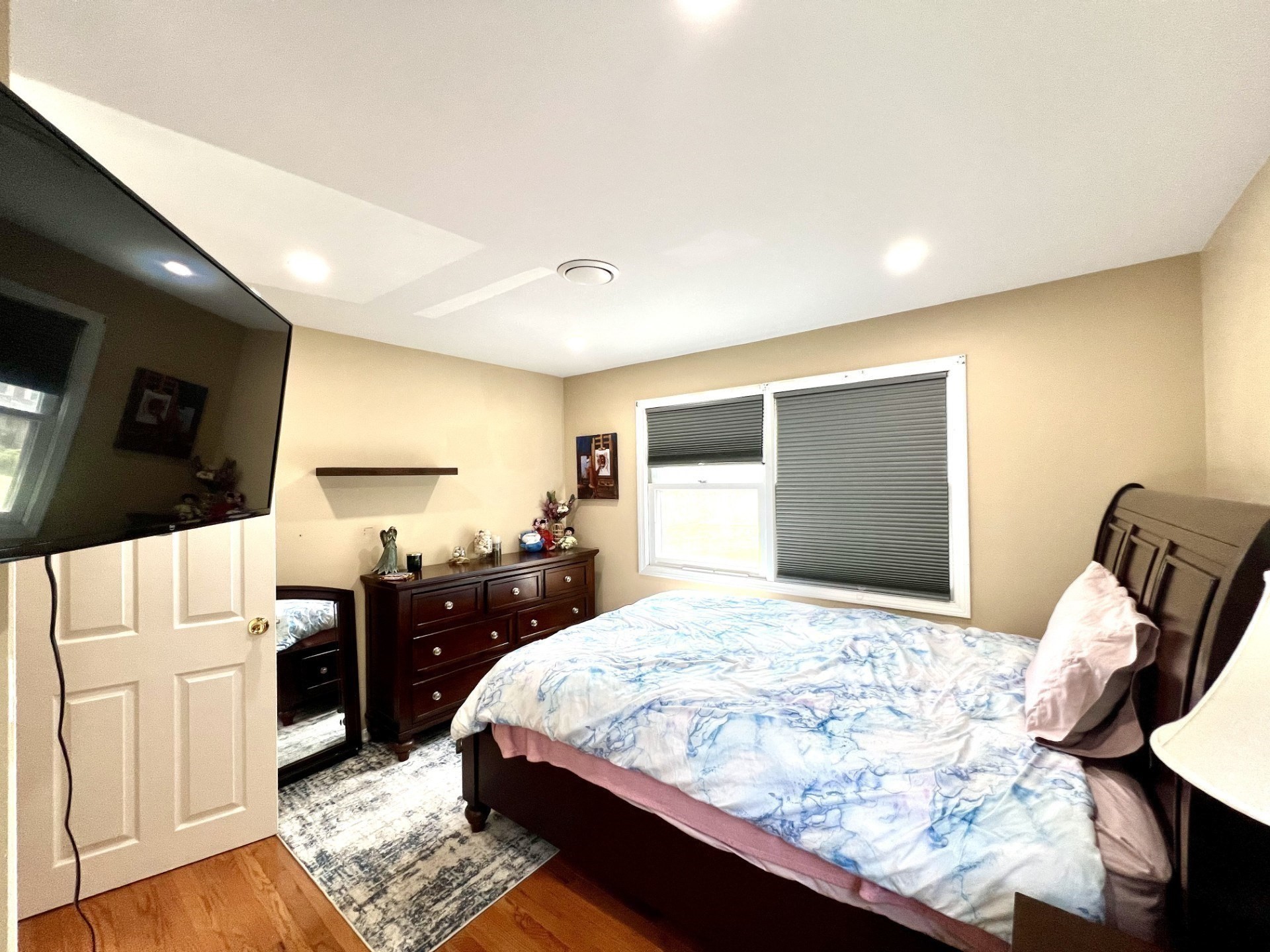 Bedroom with blue-and-white bedding, dark wood furniture, and a large wall-mounted TV.