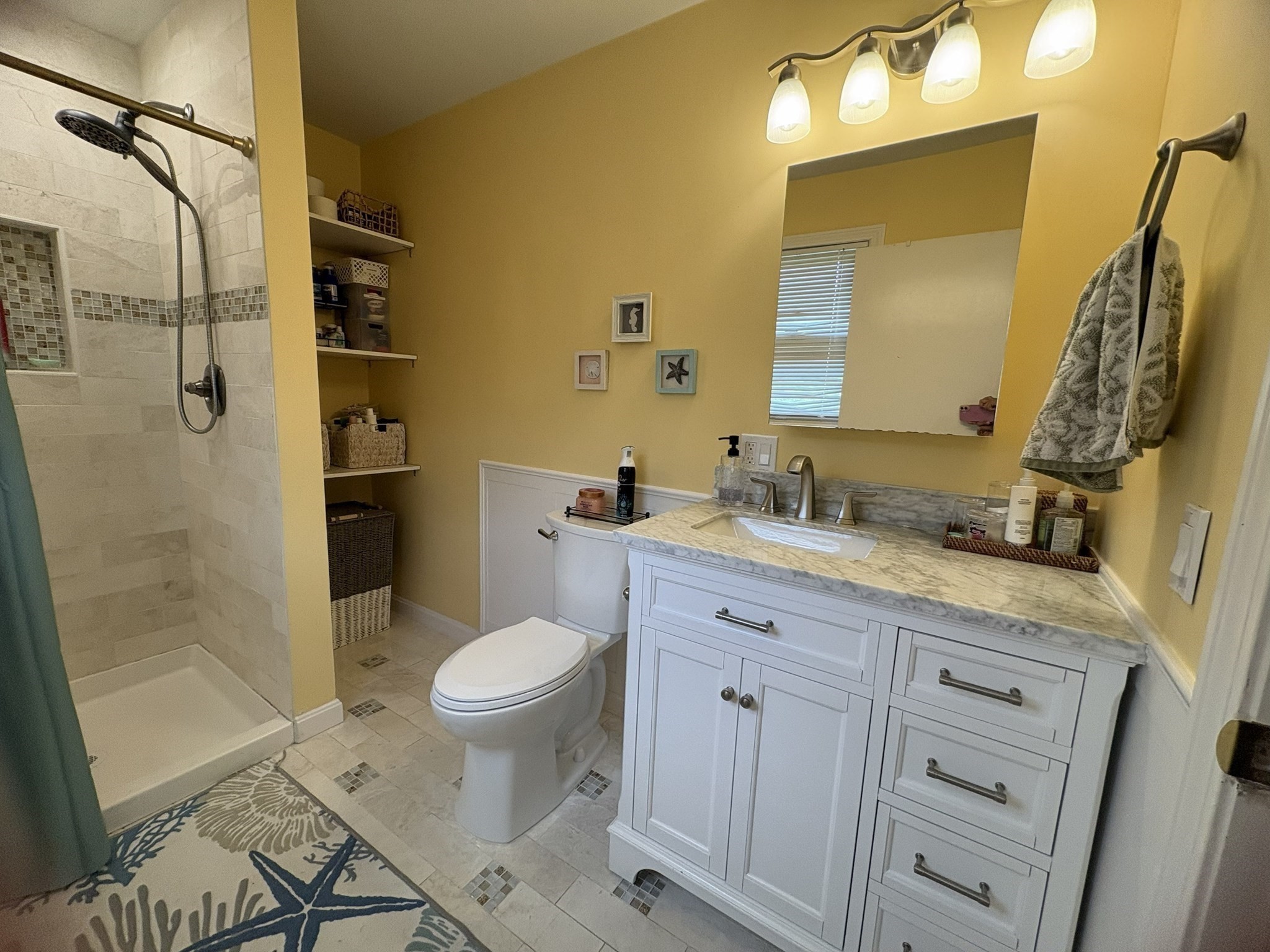 Bathroom with a white vanity, tiled shower, and built-in open shelves.