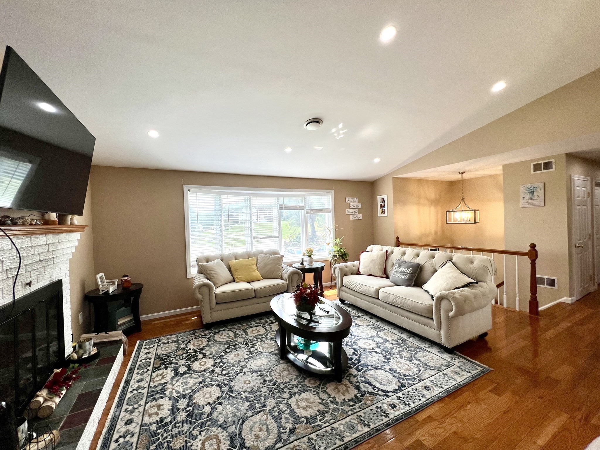 Living room with cream sofas, a patterned rug, and a white stone fireplace.