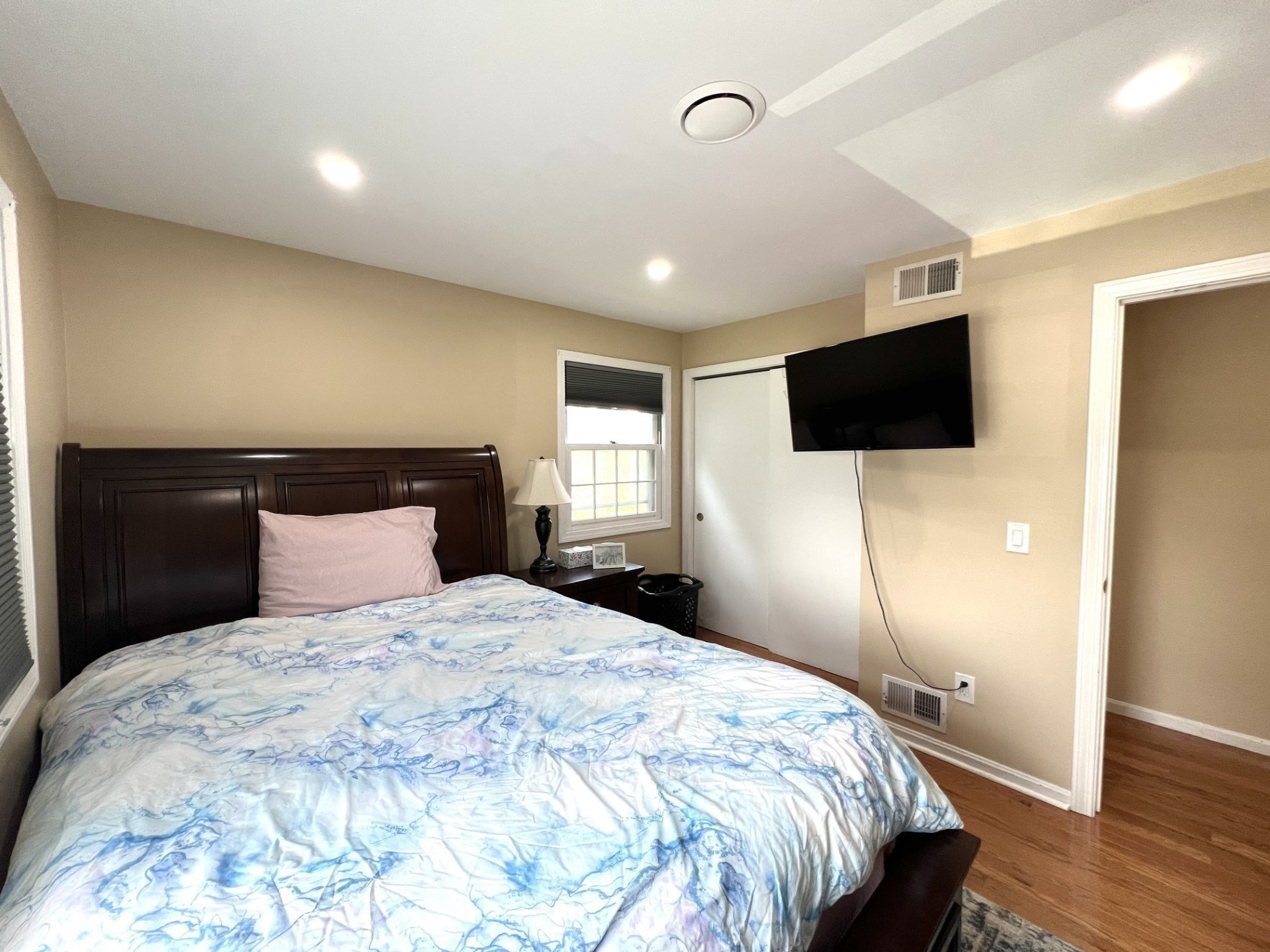 Bedroom with a dark wood bed, blue-and-white bedding, and a wall-mounted television.