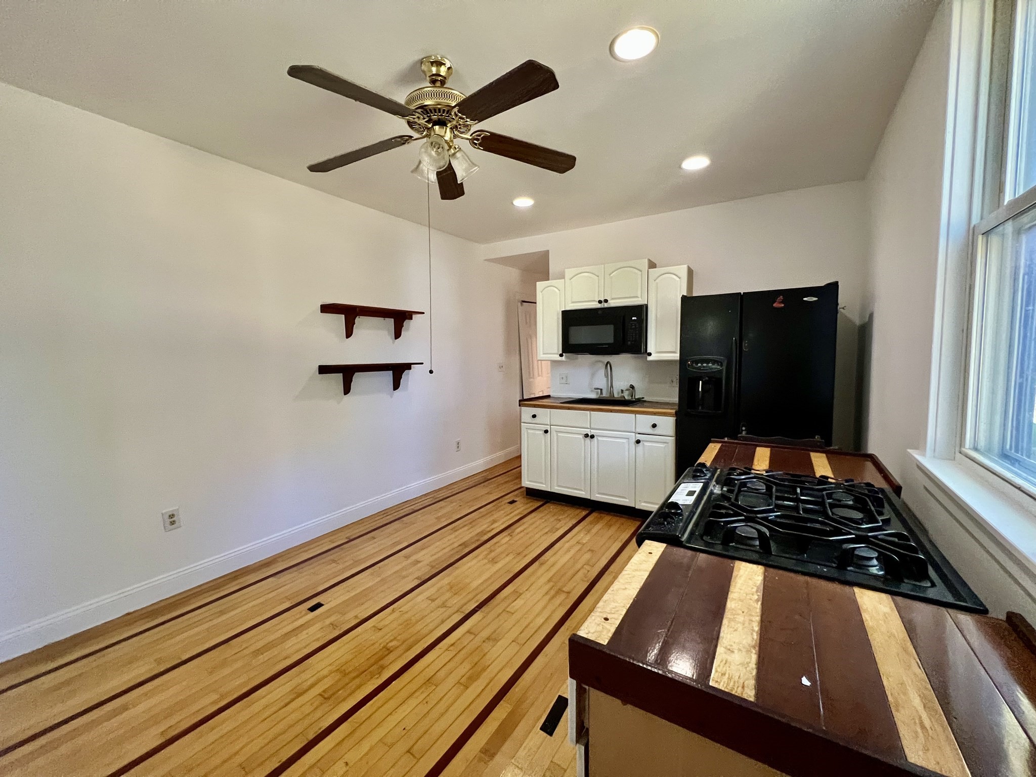 Kitchen with white cabinets, black appliances, and a striped wood floor and countertop.