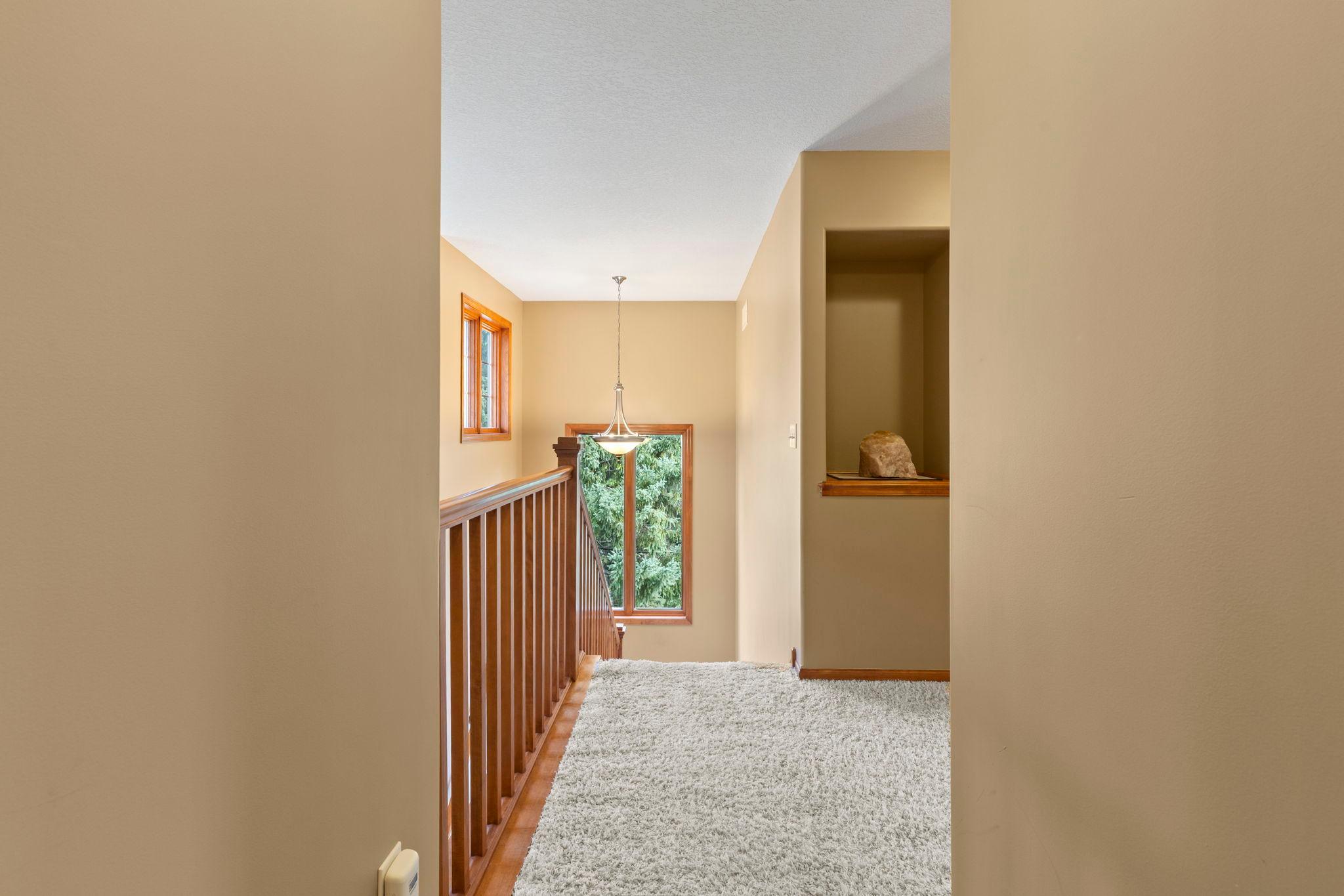 Upstairs landing with a wood railing, tall windows, and a recessed display niche.