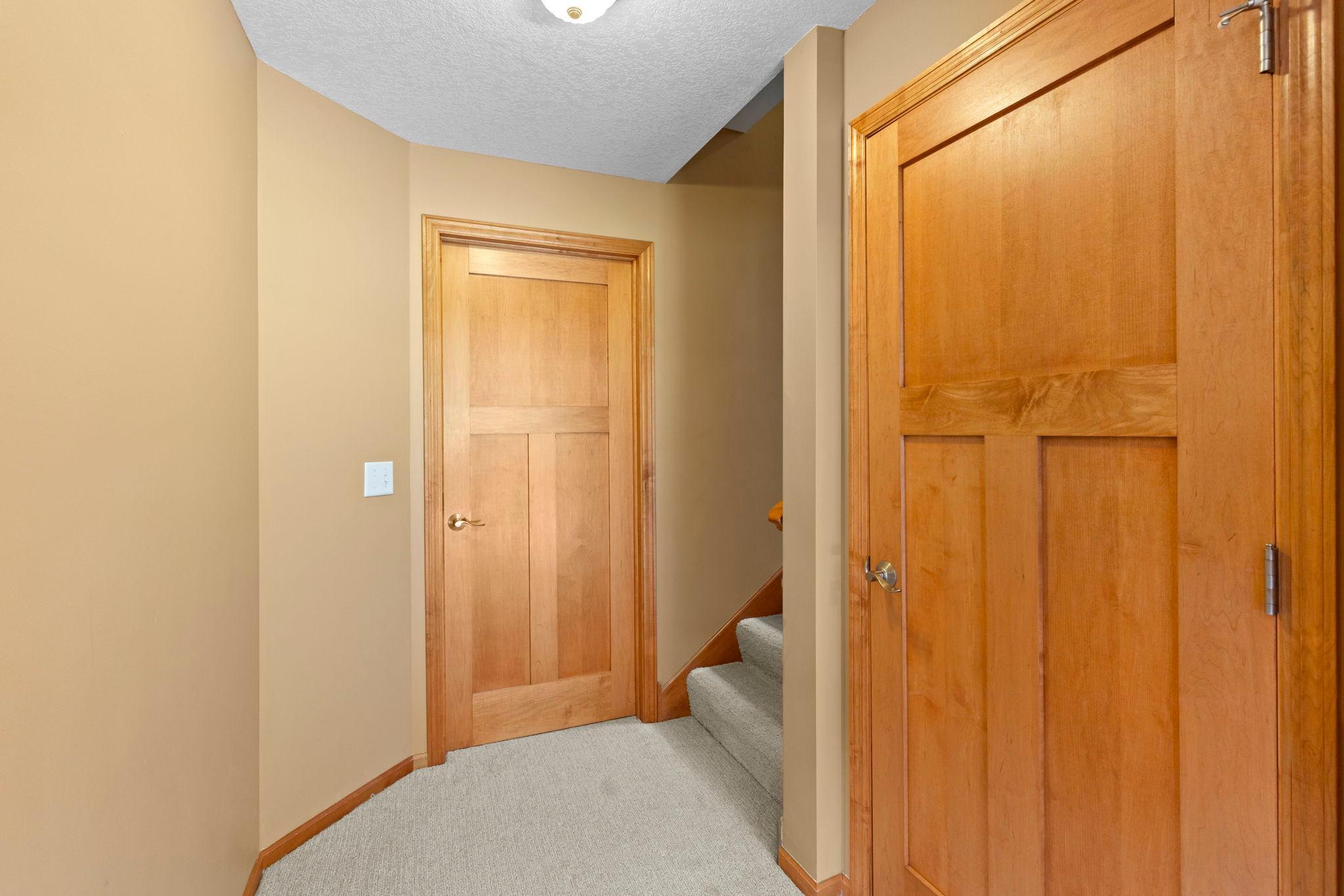 Hallway with wood-paneled doors and carpeted stairs.