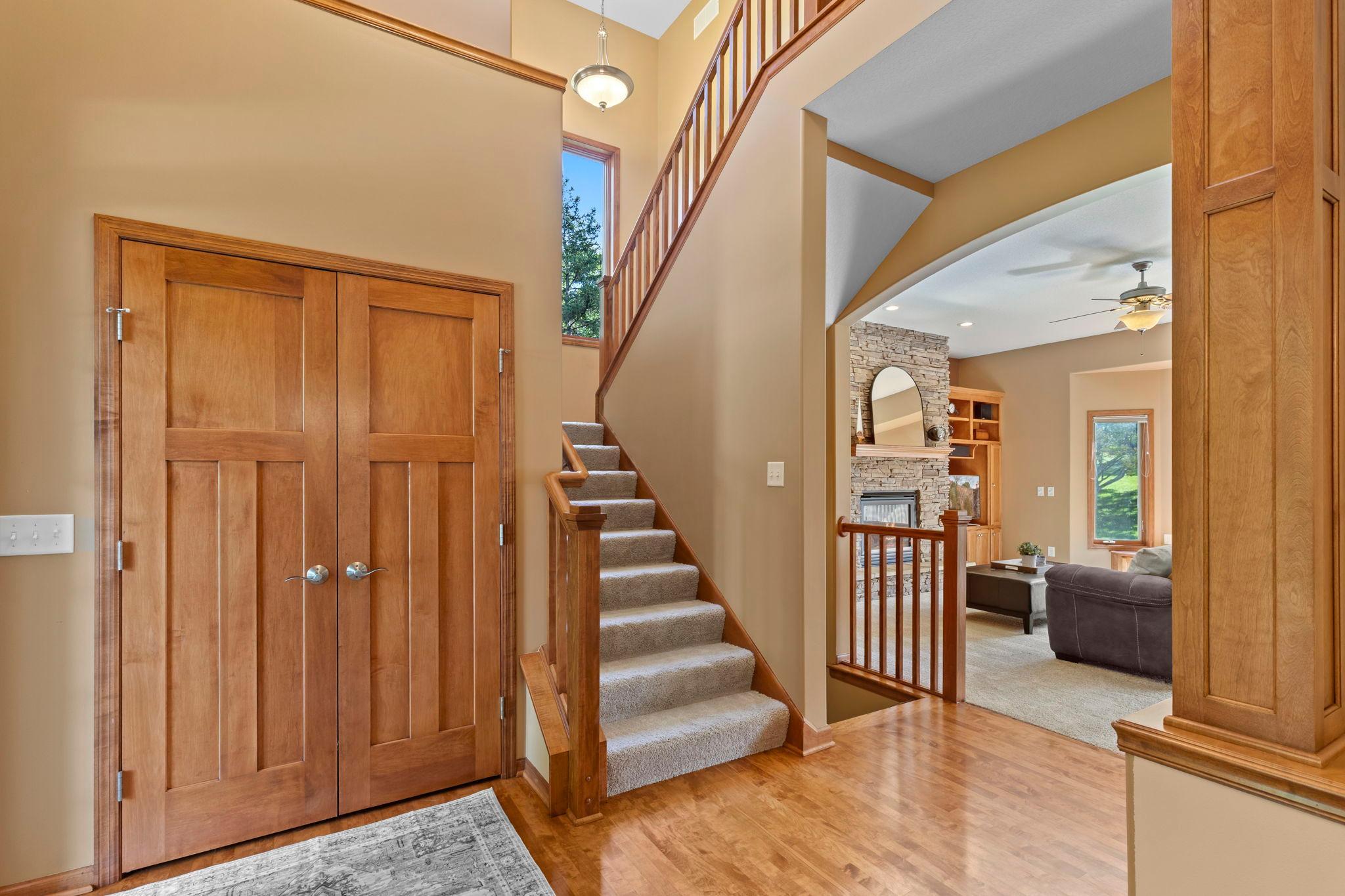 Two-story entry foyer with paneled double doors, carpeted staircase, and a view into the living room.