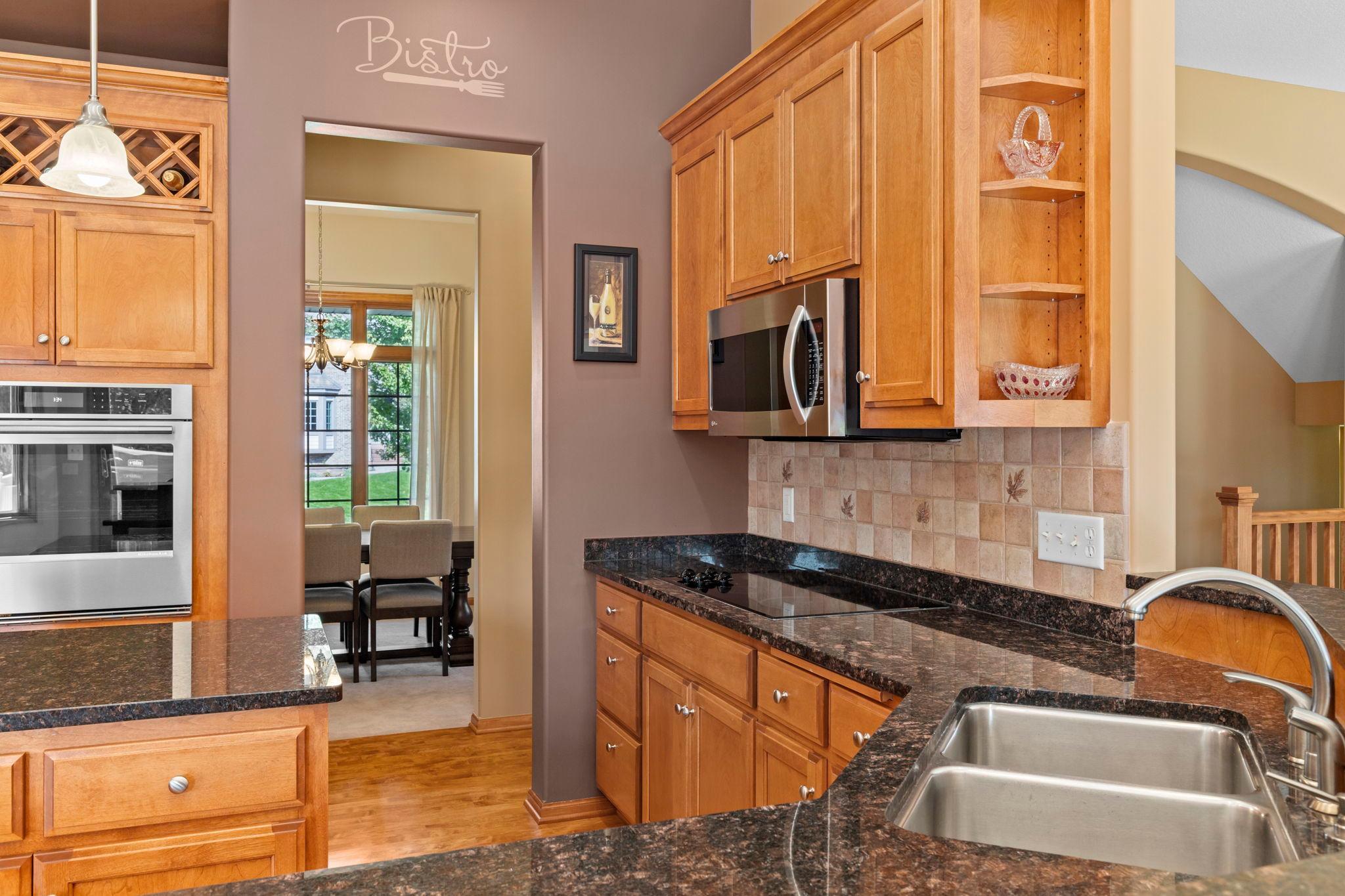 Kitchen with wood cabinetry, dark granite counters, stainless appliances, and a double-basin sink.