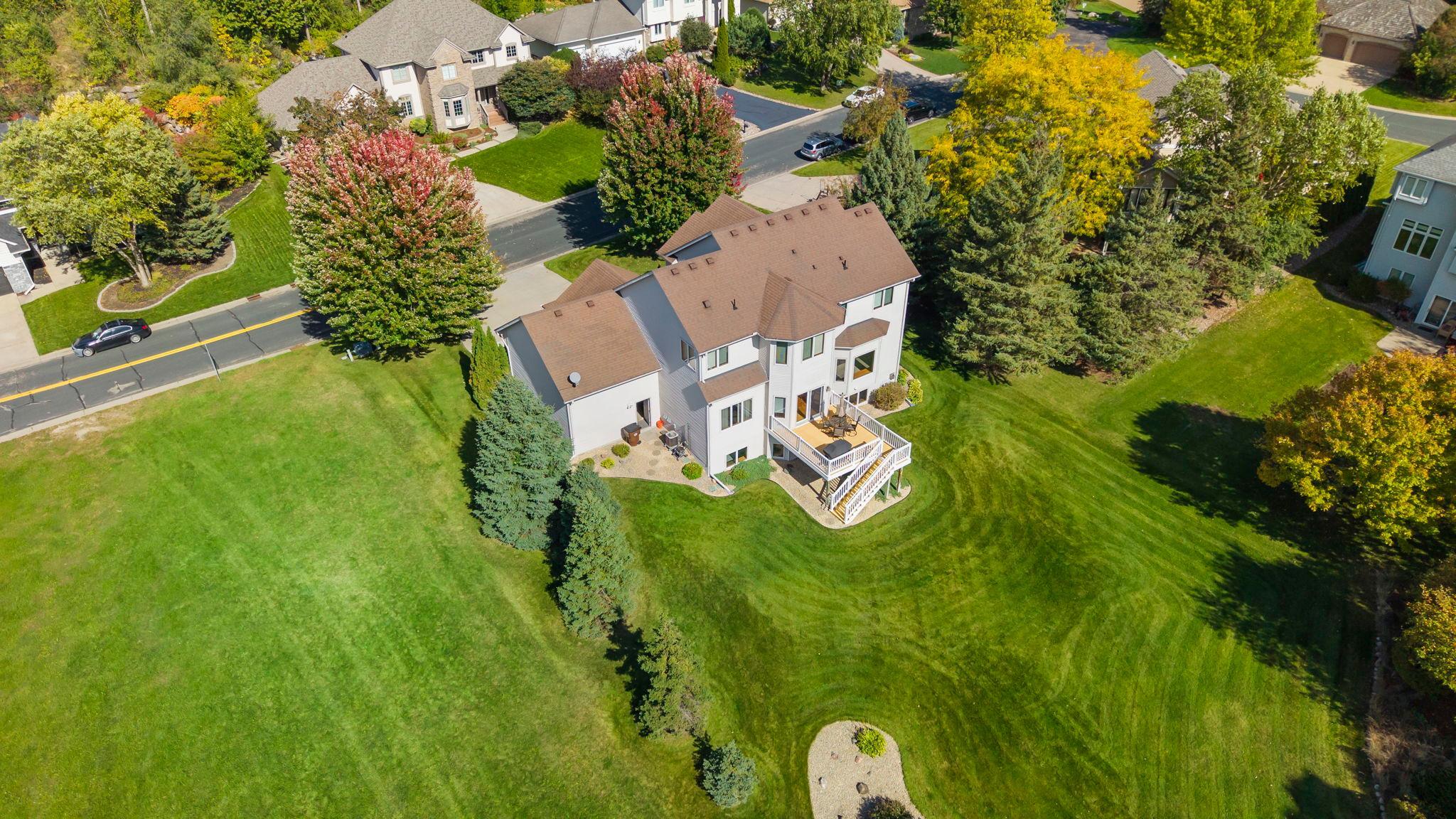 Aerial view of a two-story home with an elevated deck and expansive lawn.