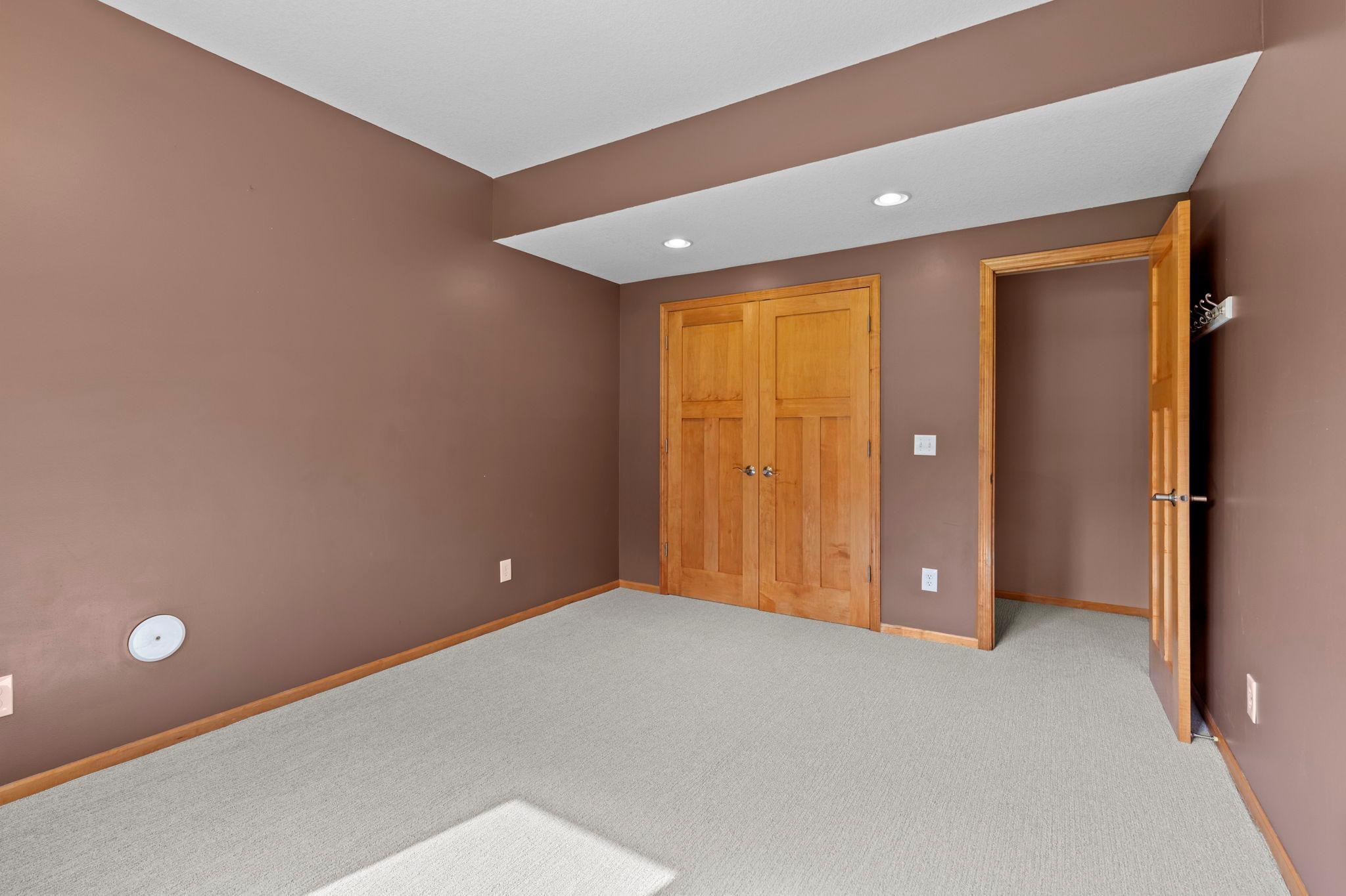 Empty carpeted room with brown walls and wooden double closet doors.