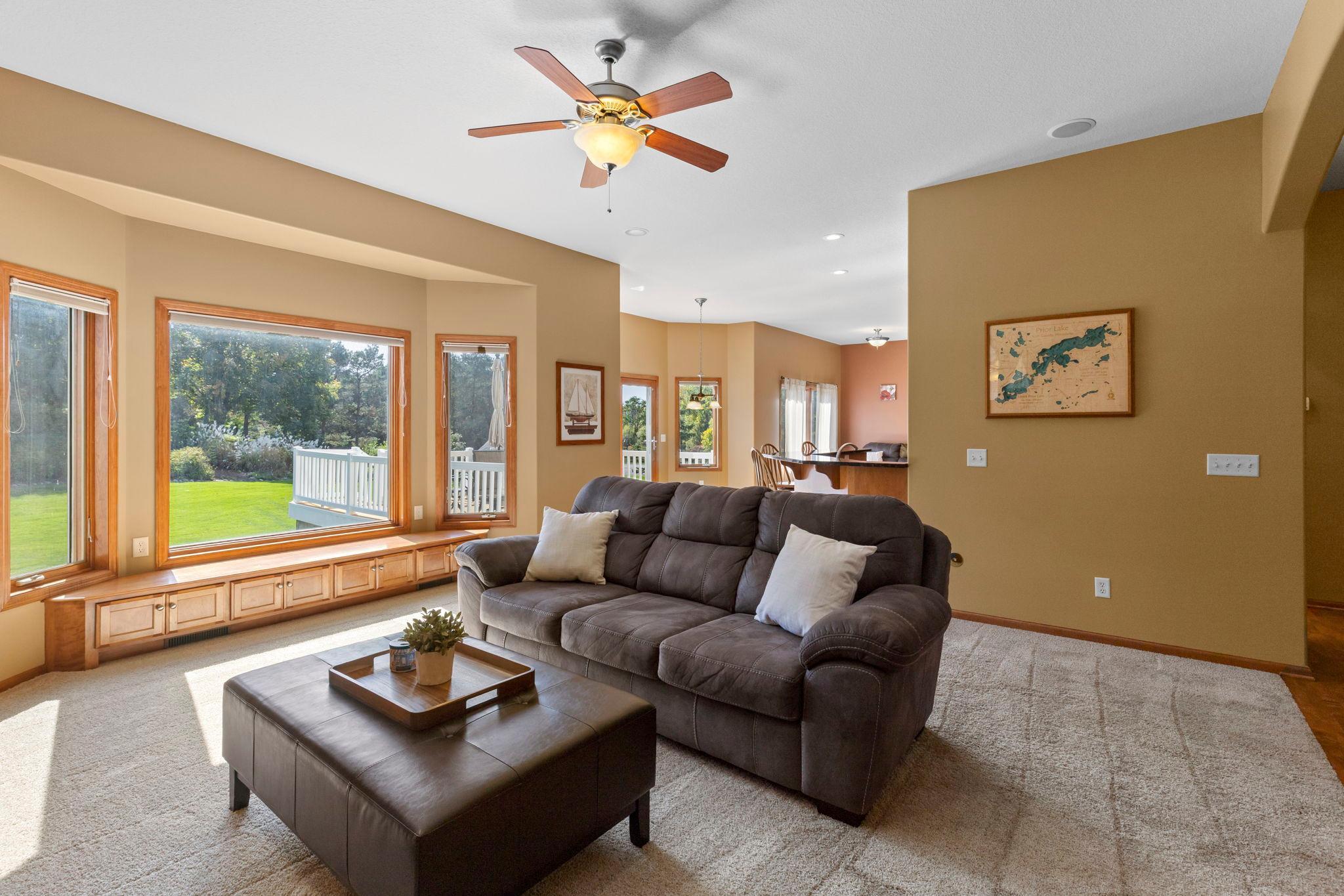 Living room with a gray sectional sofa and large windows overlooking a deck and lawn.
