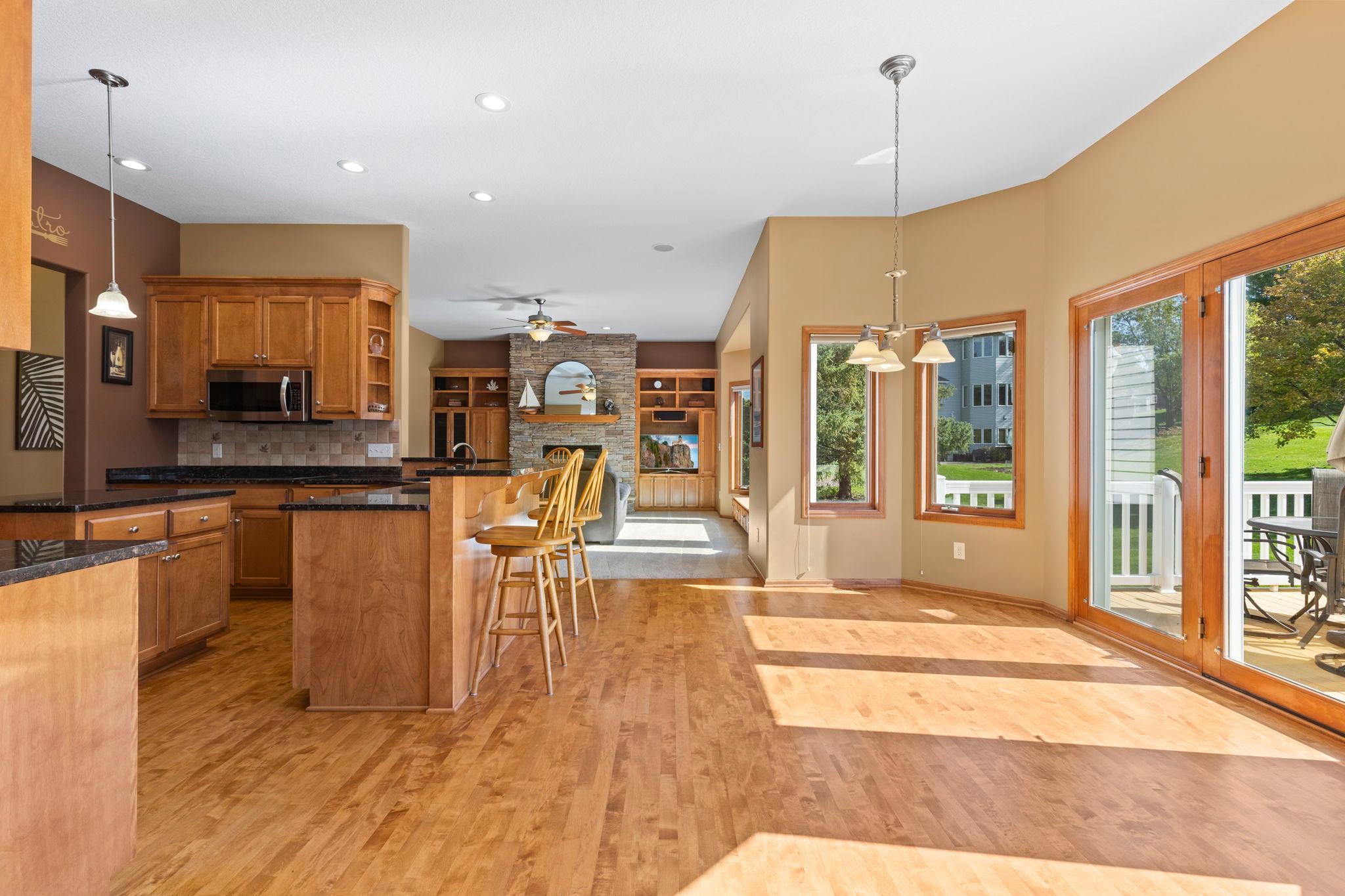 Open kitchen and dining area with wood cabinetry, hardwood floors, and sliding glass doors to a deck.