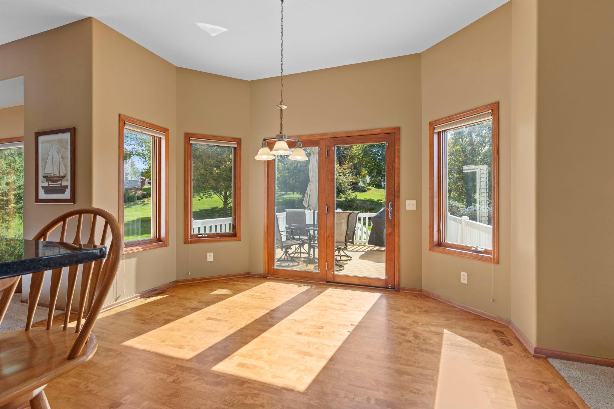 Dining area with parquet floors, wood-trimmed windows, and sliding doors to a sunny deck.