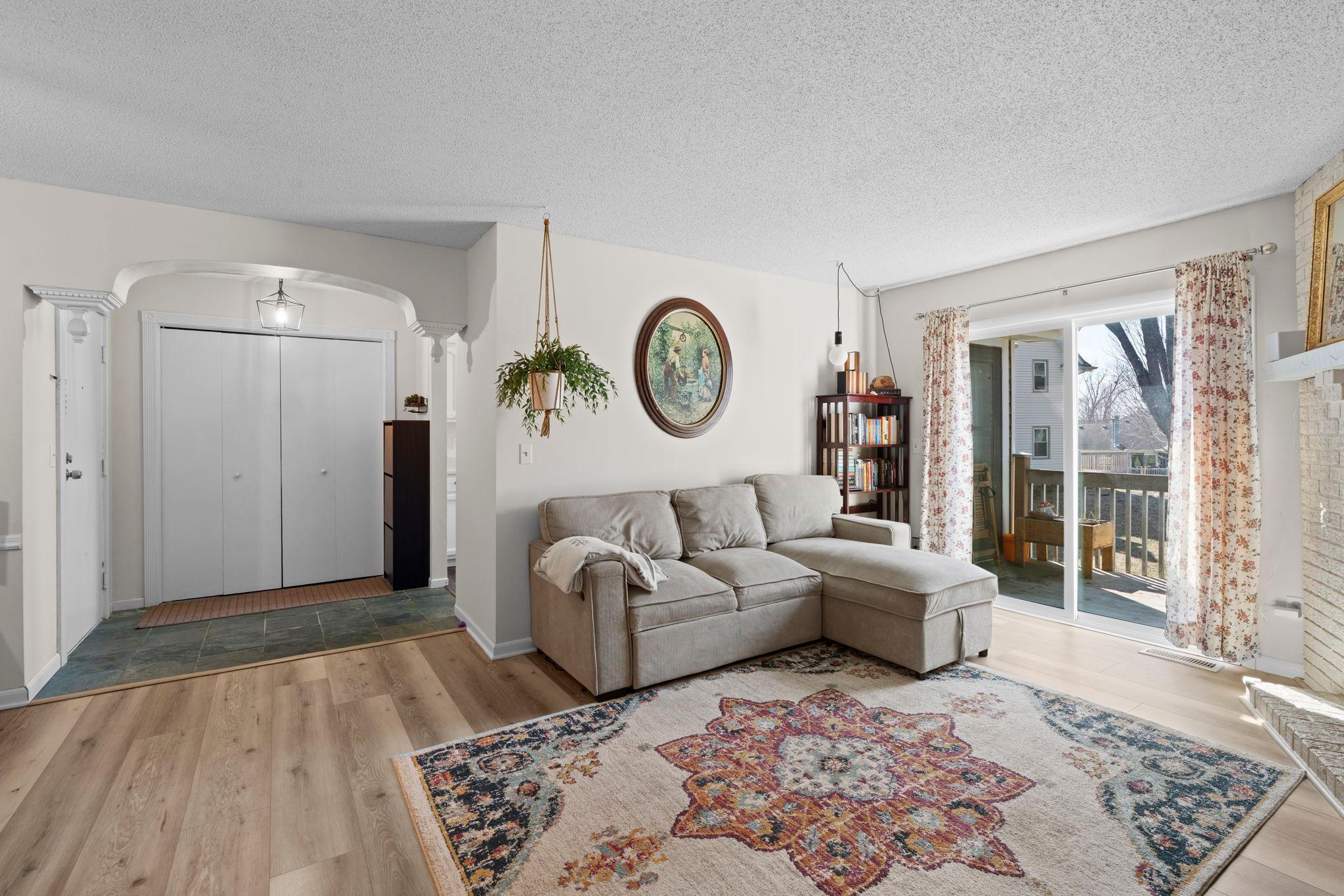 Living room with a gray sectional, patterned rug, and sliding doors to a deck.