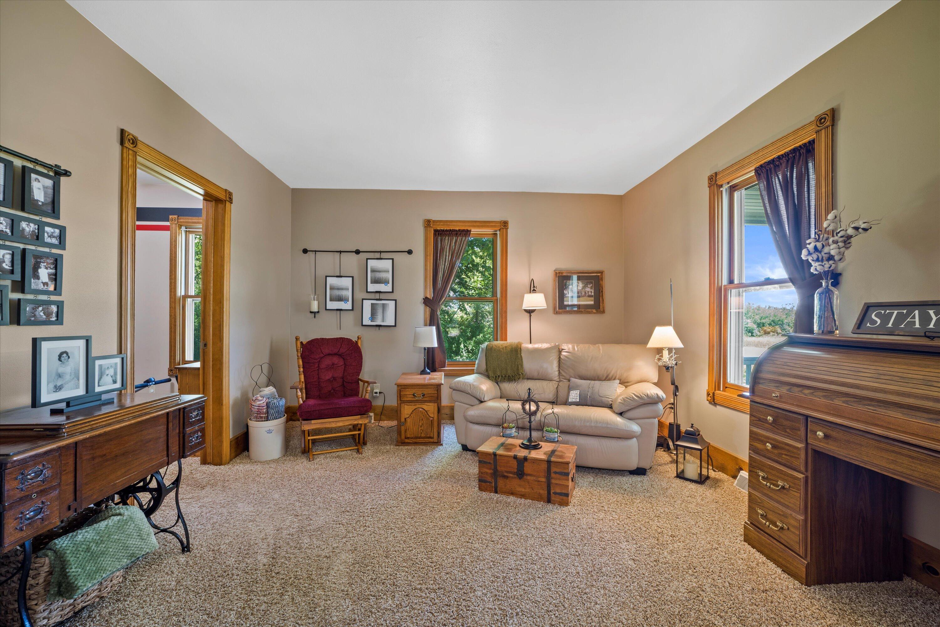Living room with a cream sofa, burgundy armchair, large windows, and ornate wood trim.
