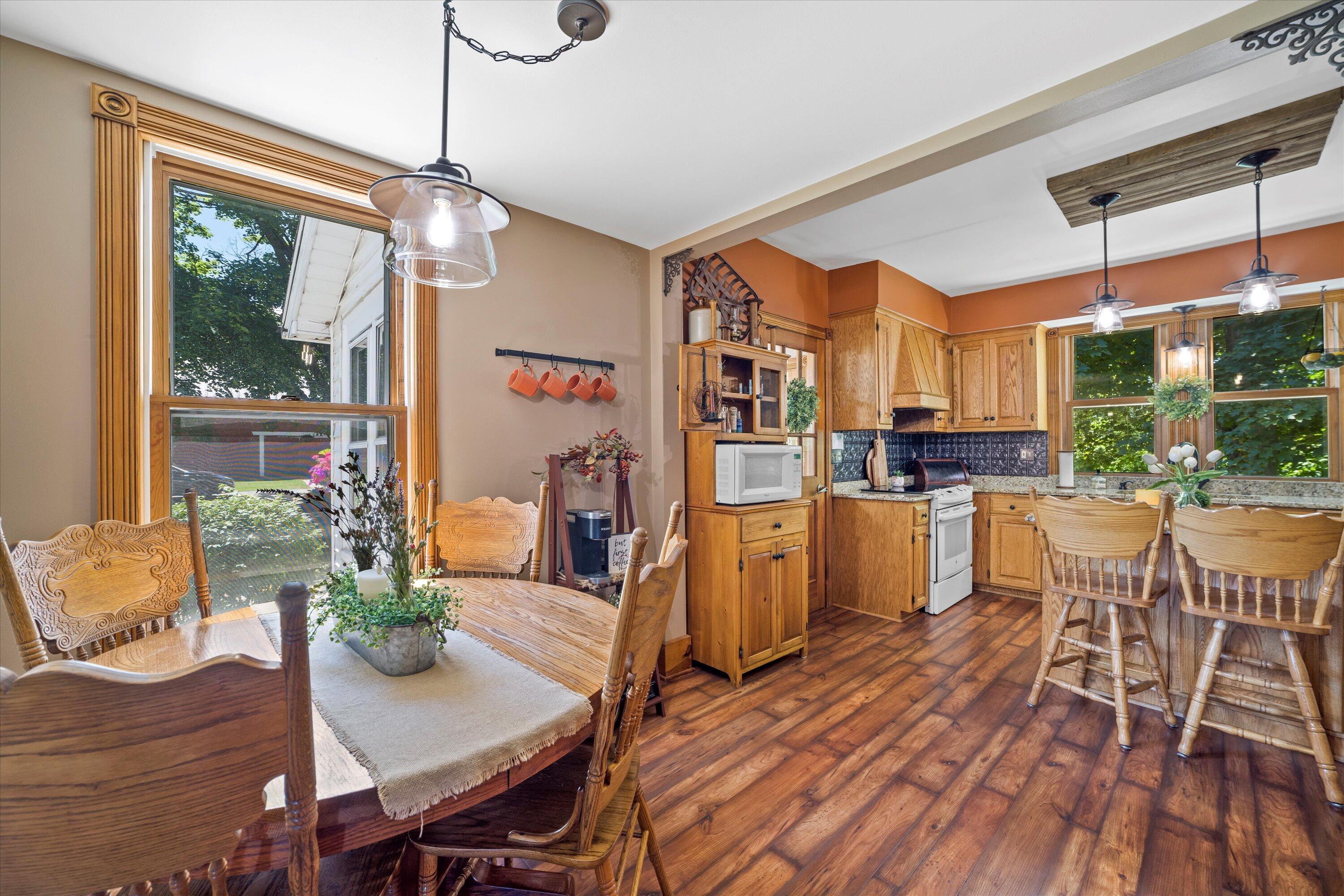 Kitchen and dining area with warm wood cabinets, a large window, and a wooden breakfast bar.