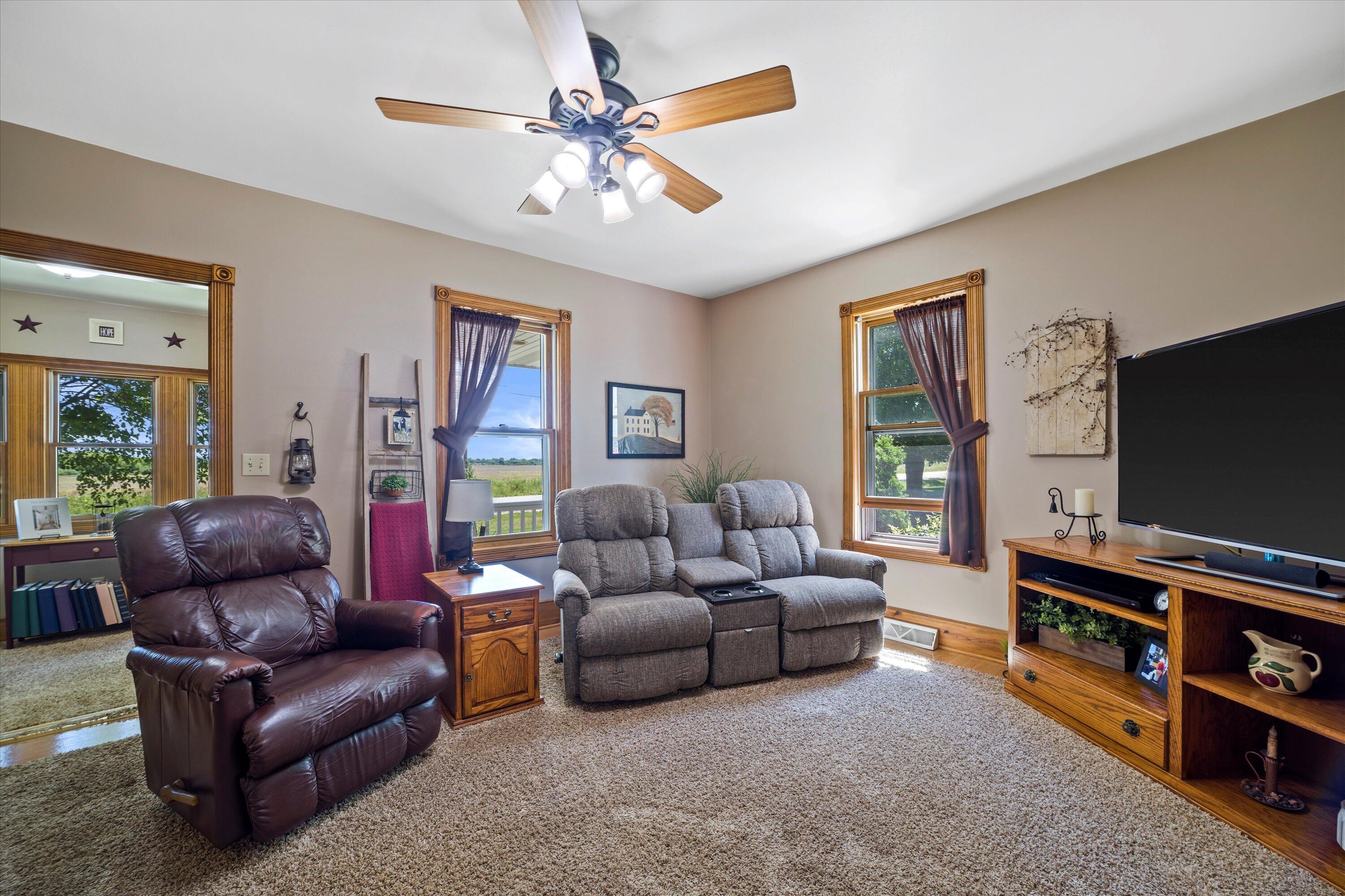 Living room with reclining sofa, leather armchair, and wood-trimmed windows.