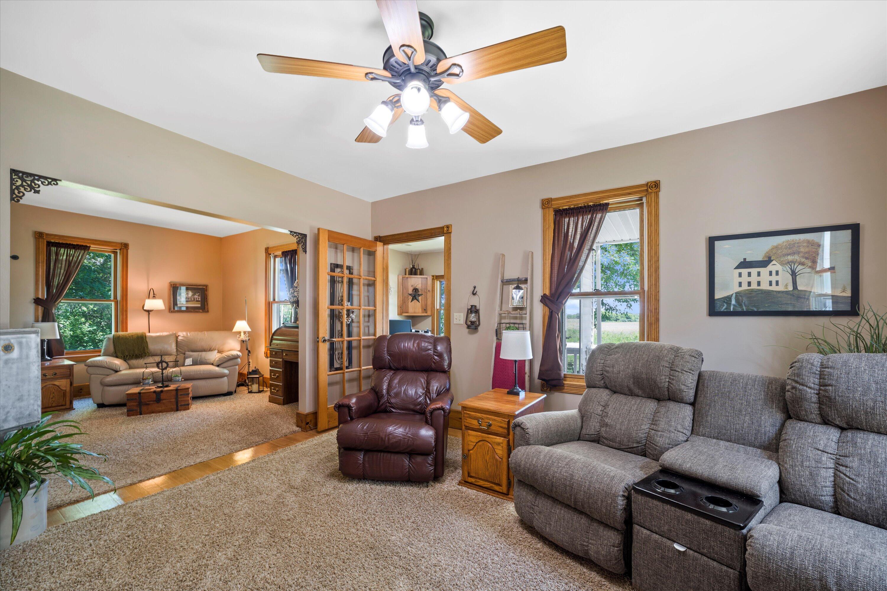 Furnished living room with a gray reclining sofa, leather armchair, and ceiling fan.