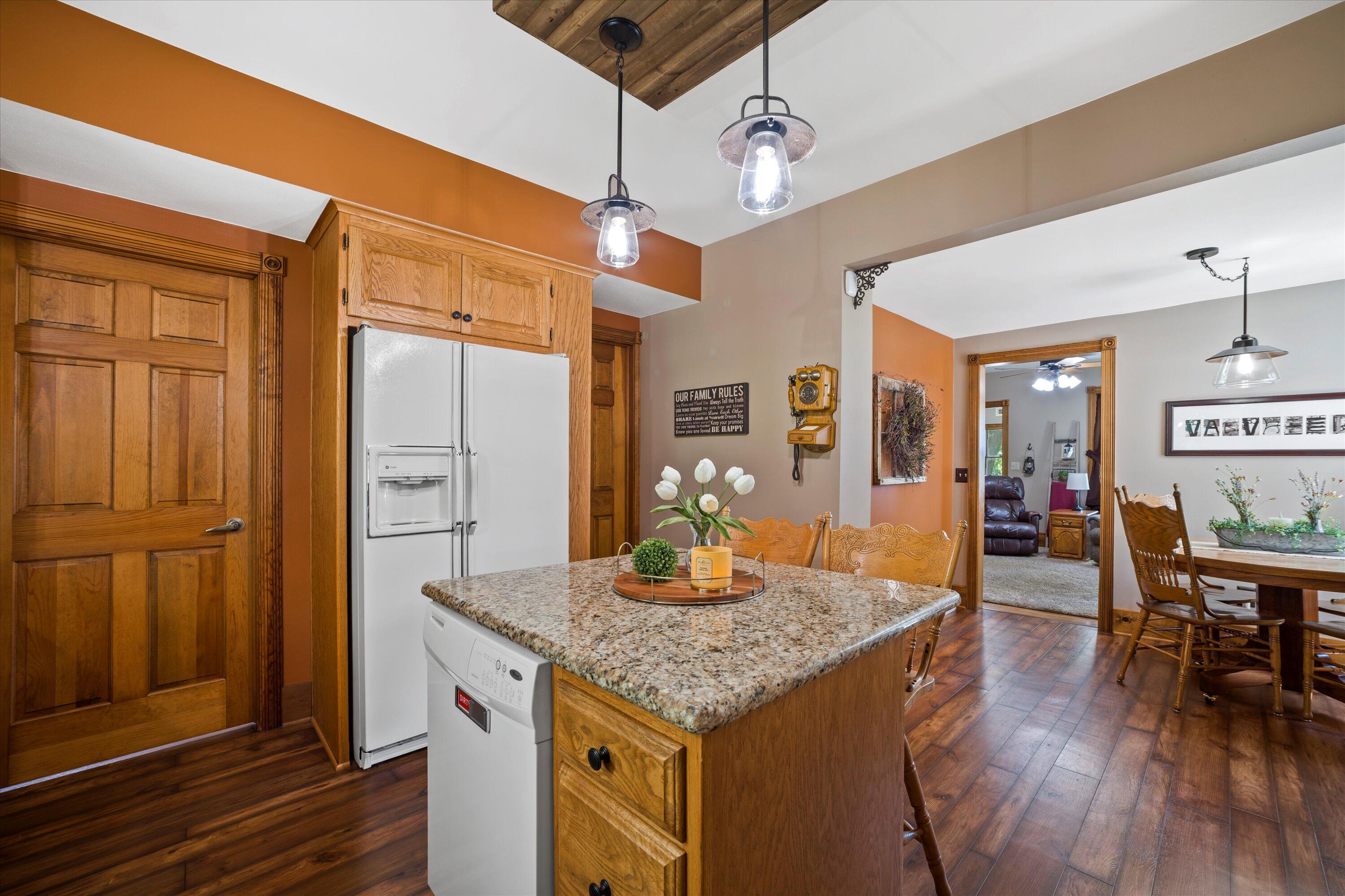 Kitchen with a granite island, warm wood cabinetry, and an adjoining dining area.