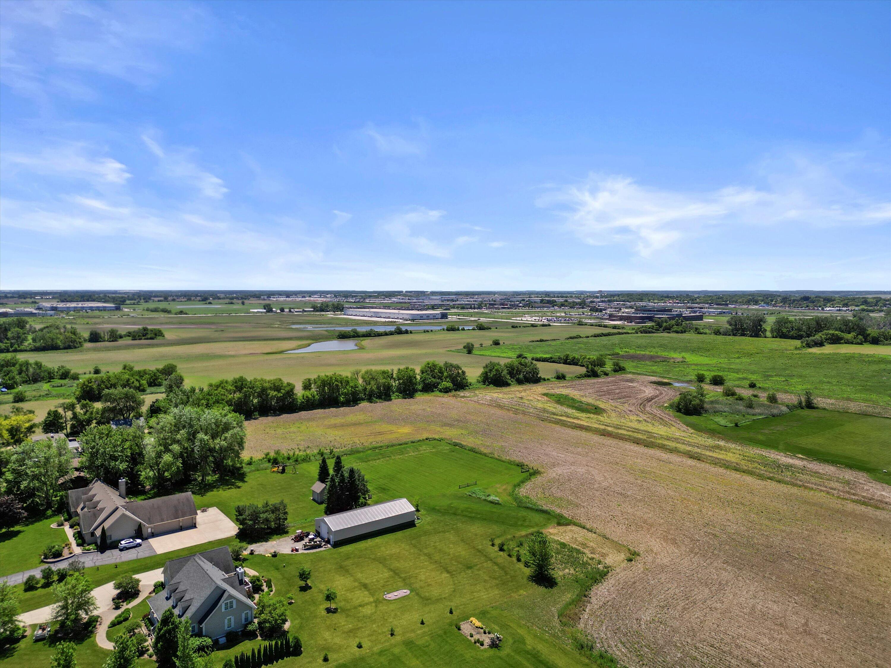 Aerial view of the property’s lawns, fields, homes, and distant commercial buildings.