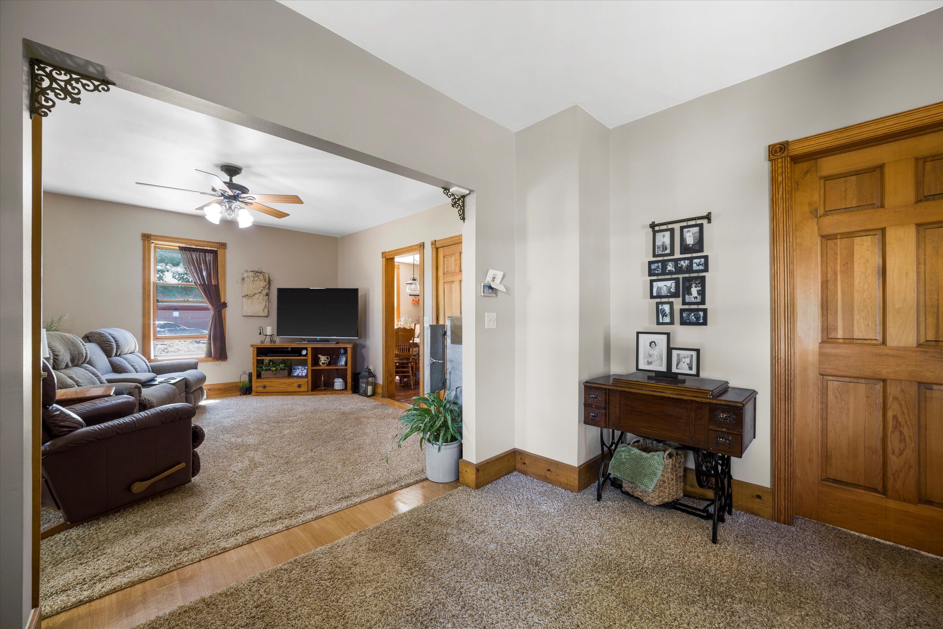 Furnished living room with reclining sofas, a ceiling fan, and a wood-trimmed opening to the adjoining sitting area.