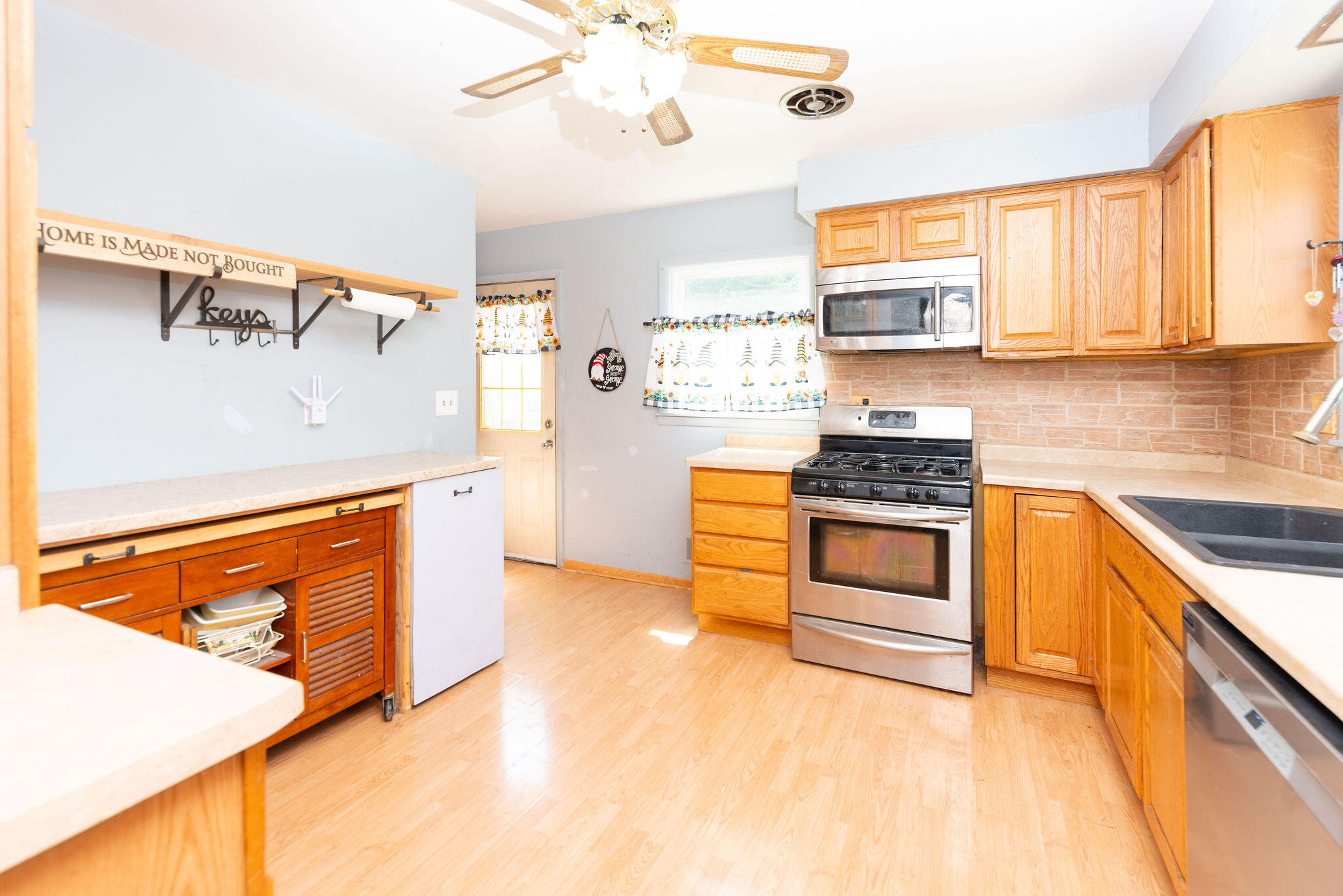 Kitchen with honey-colored wood cabinets, stainless steel range, and pale countertops.