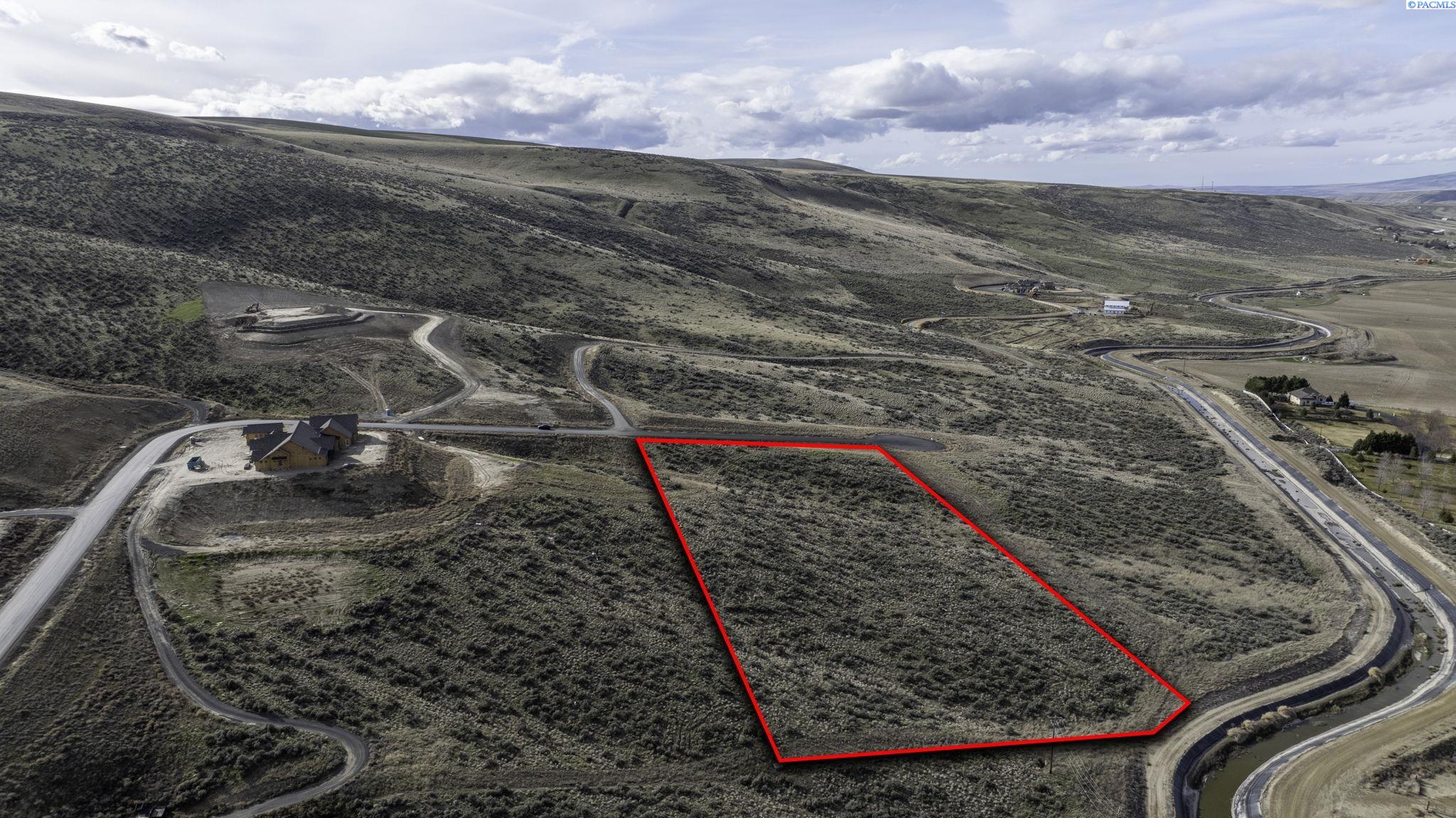Vacant scrub-covered land parcel outlined in red, surrounded by winding roads and rolling hills.