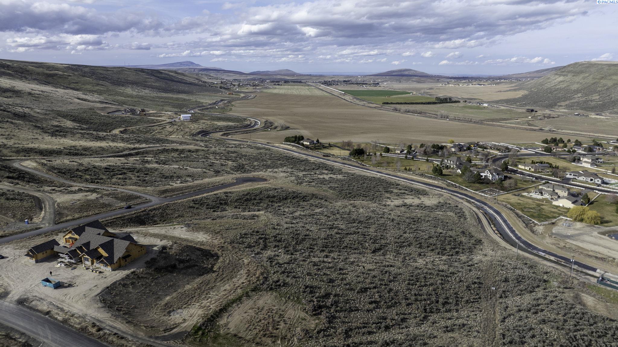 Aerial view of a rural parcel with a home under construction and open scrubland.