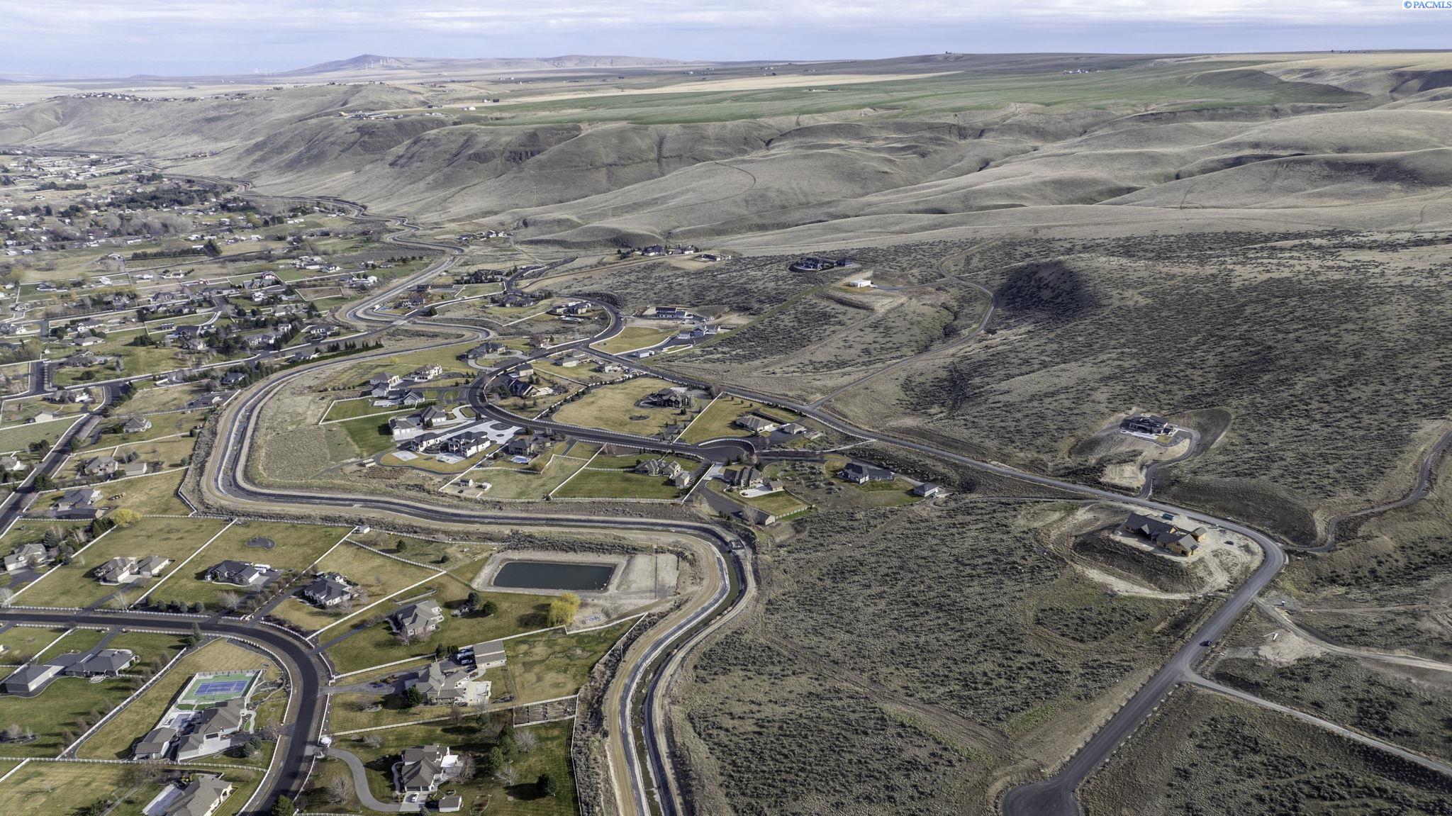 Aerial view of homes and winding roads amid rolling, sparsely vegetated hills.