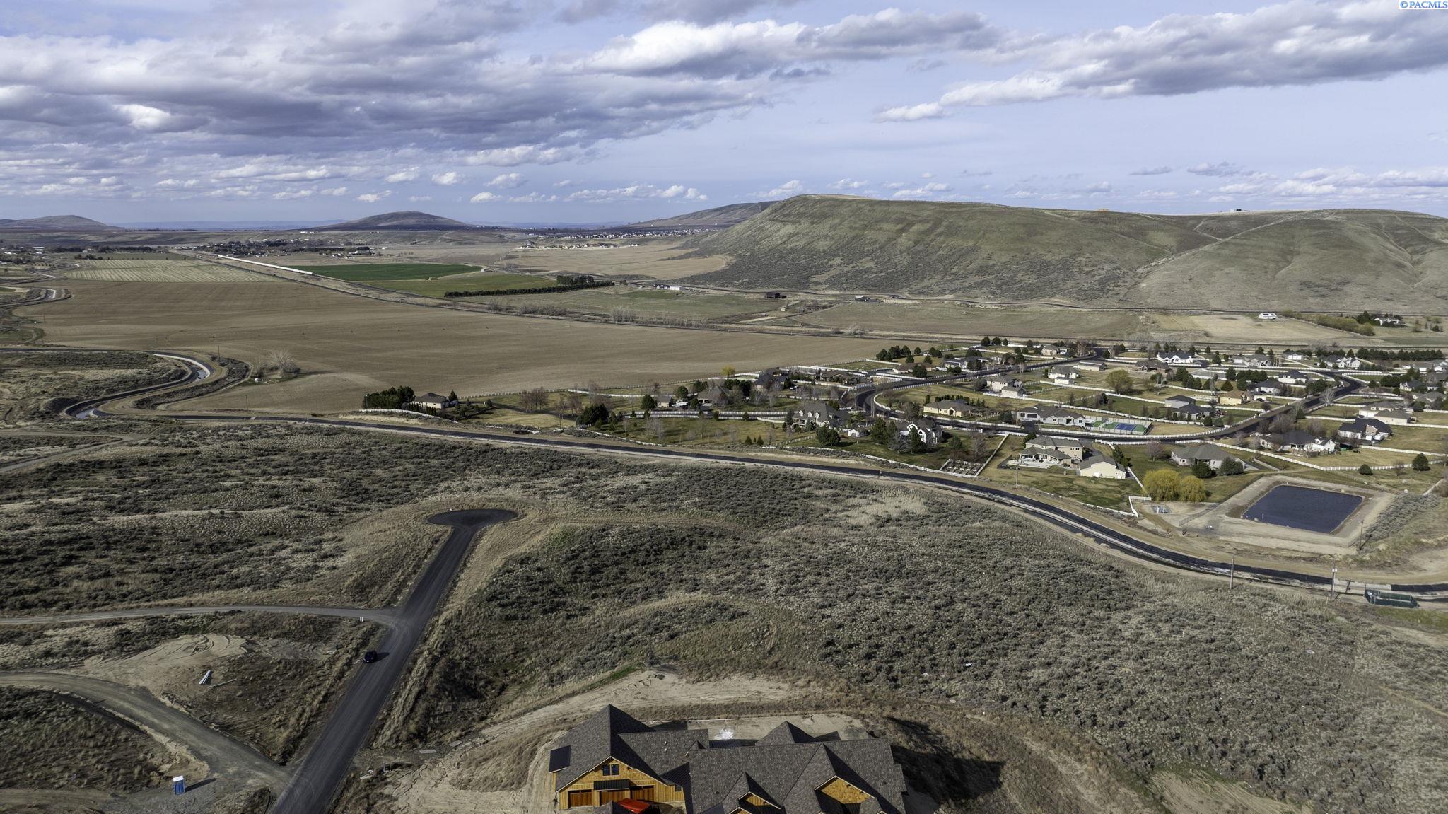 Aerial view of a Kennewick property and surrounding hills, fields, and neighborhood.