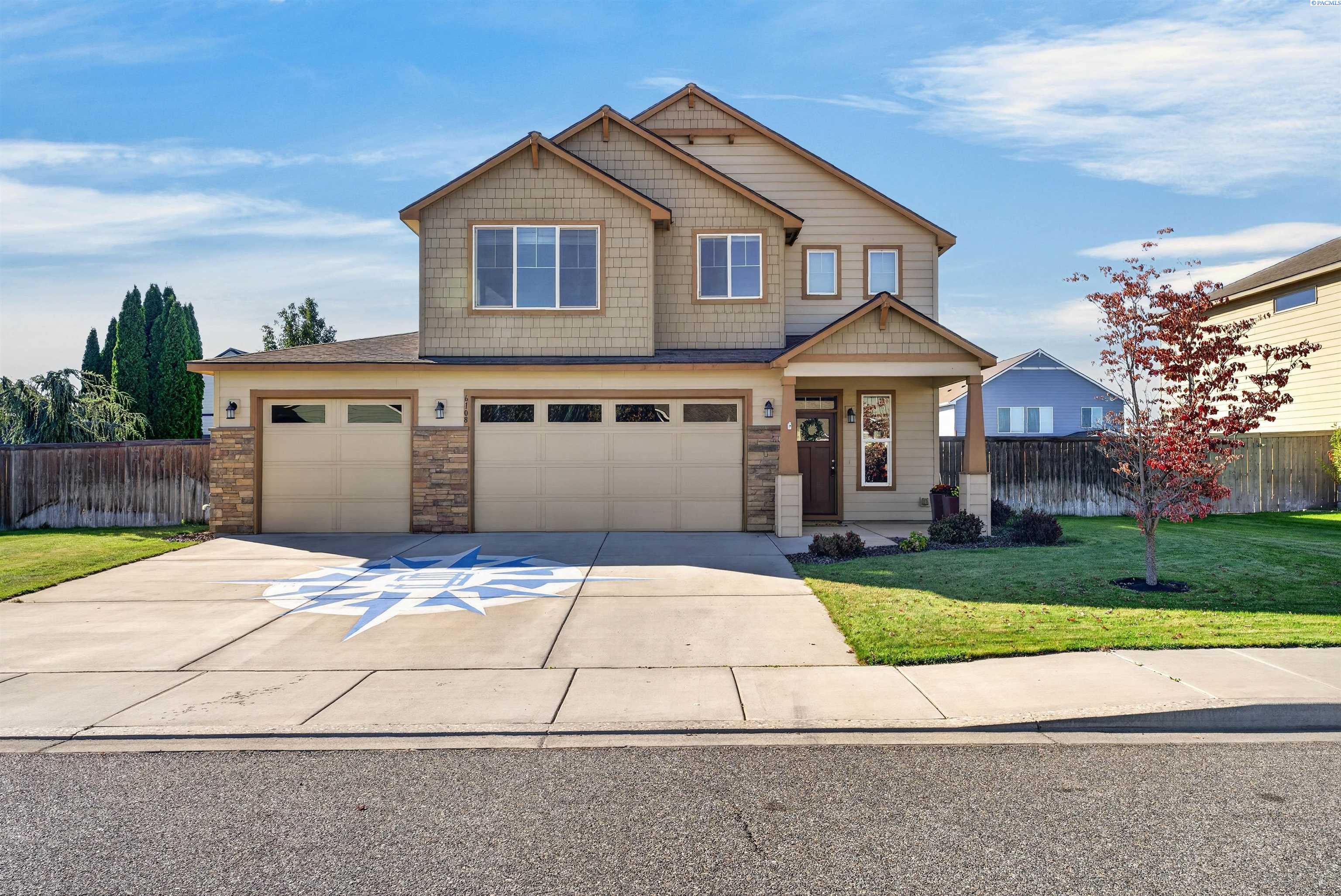 Two-story beige house with a two-car garage and compass rose painted on the driveway.
