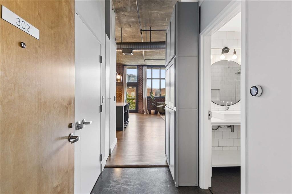 Apartment entry hallway leading to a bright loft living area, with a tiled bathroom on the right.
