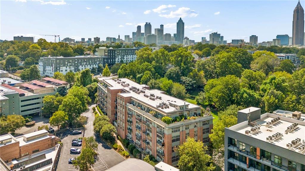 Aerial view of a residential building amid leafy trees, with the Atlanta skyline in the distance.
