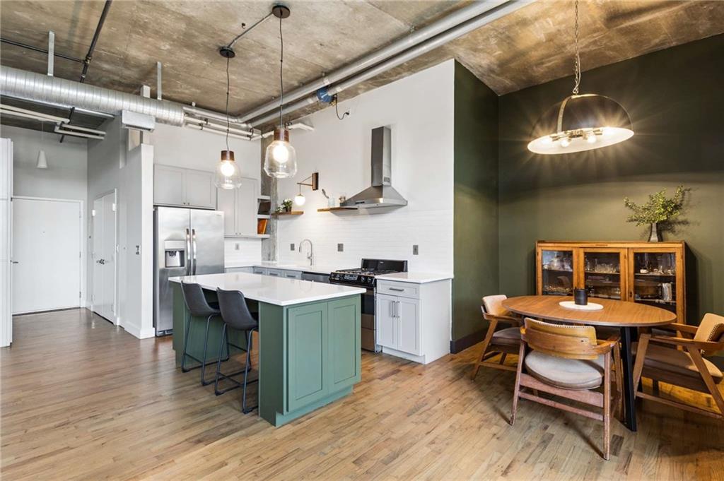 Open-plan kitchen with a green island, stainless steel appliances, and adjoining wood dining area.