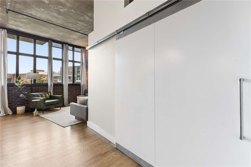 Condo living room with tall windows, exposed concrete ceiling, and a large white sliding door.