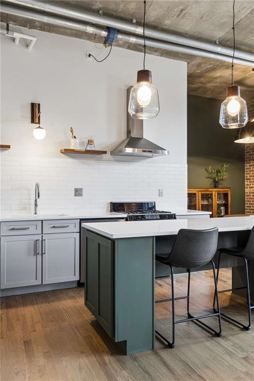 Modern kitchen with a dark green island, white tile backsplash, and glass pendant lights.