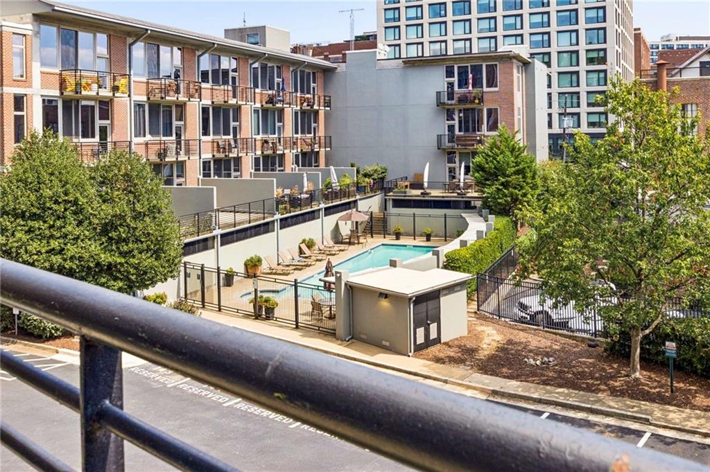 Condominium courtyard with a fenced swimming pool, lounge chairs, and balconies.