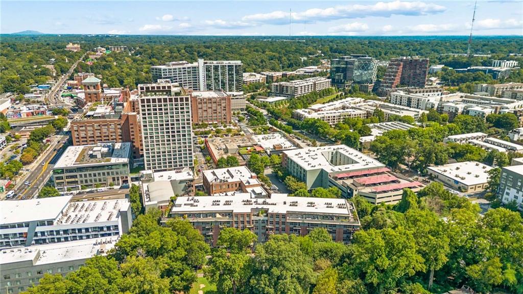 Aerial view of Atlanta’s leafy urban neighborhood, with mid-rise buildings and a wooded horizon.