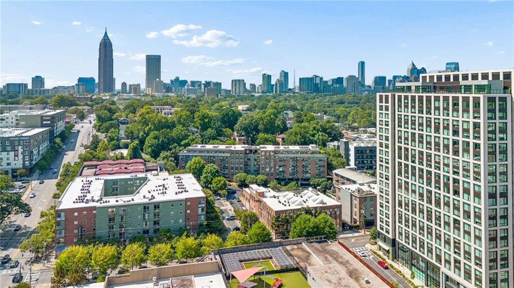 Atlanta skyline beyond leafy Midtown buildings, viewed from an elevated vantage.