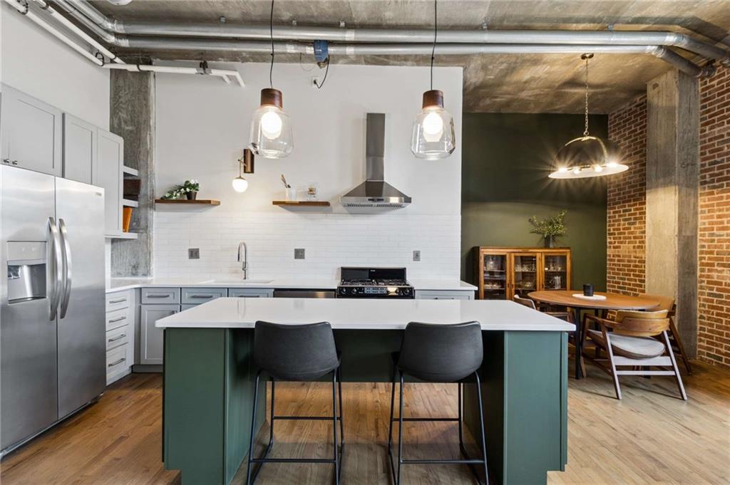 Open-plan kitchen with a large green island, stainless steel appliances, and an adjacent dining area.