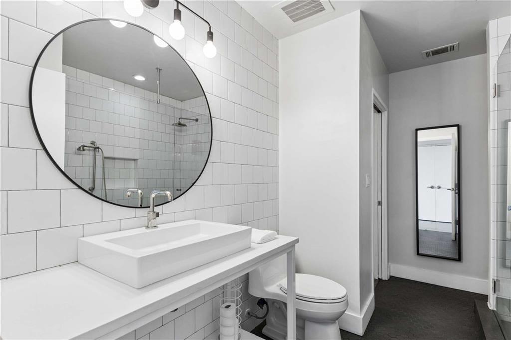 Bathroom with white subway tile, a rectangular vessel sink, and a large round mirror above the vanity.