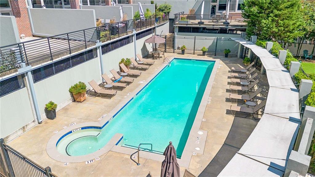 Outdoor condominium pool with a rounded shallow section and lounge chairs on the sun deck.