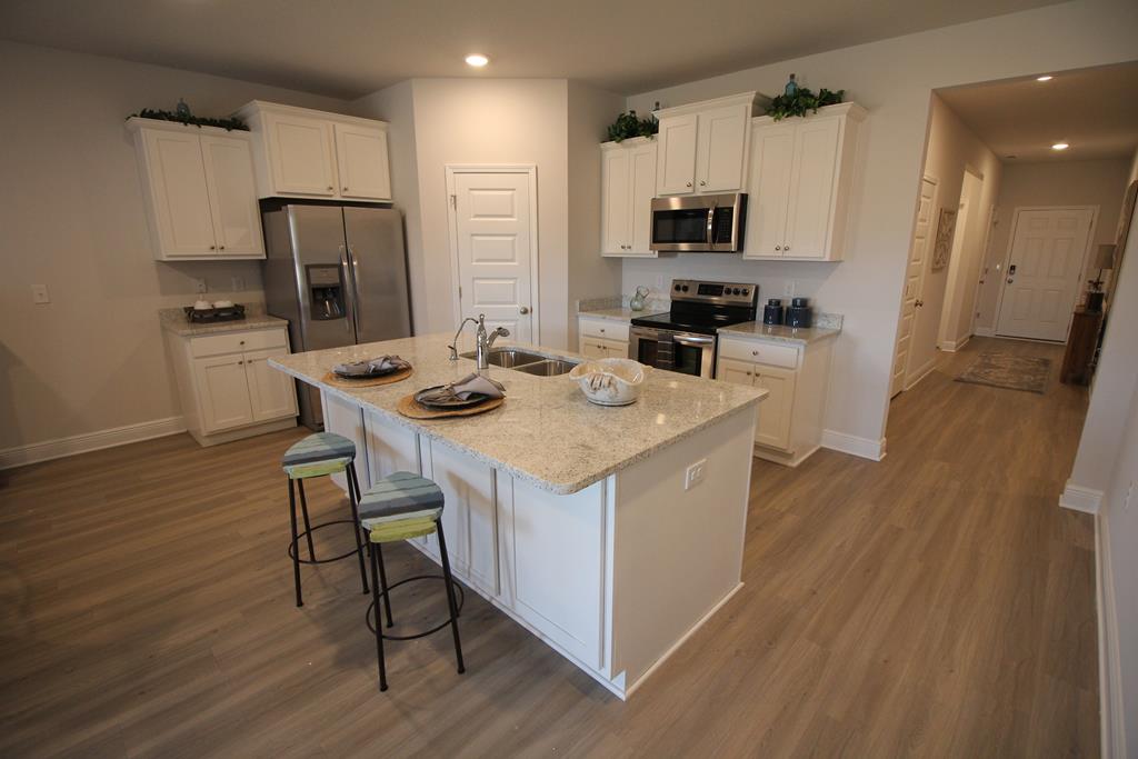 Kitchen with white cabinets, stainless steel appliances, and a large granite-topped island.