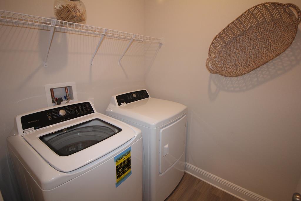 Laundry room with a white washer and dryer, wire shelf, and woven wall basket.