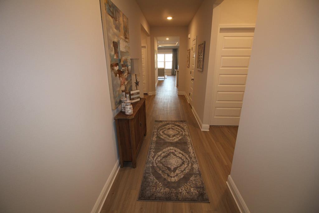 Furnished hallway with wood floors, a patterned runner, and a console beneath abstract art.