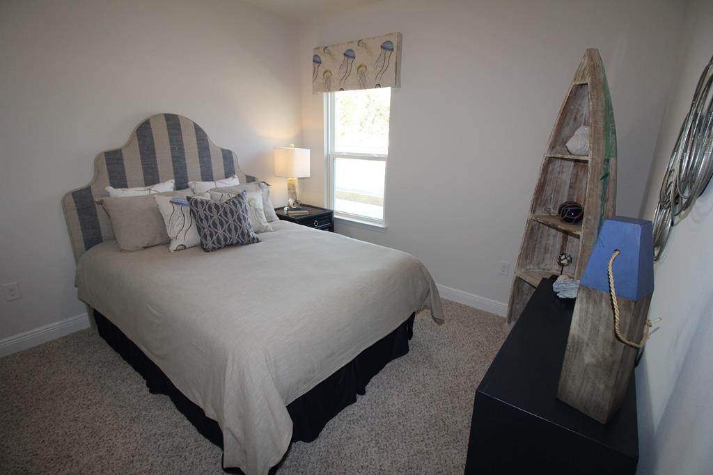 Furnished bedroom with a striped headboard, jellyfish artwork, and weathered boat-shaped shelving.