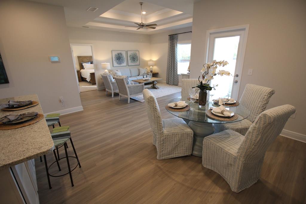 Open-plan dining and living area with a glass table, woven chairs, and a pale sofa.