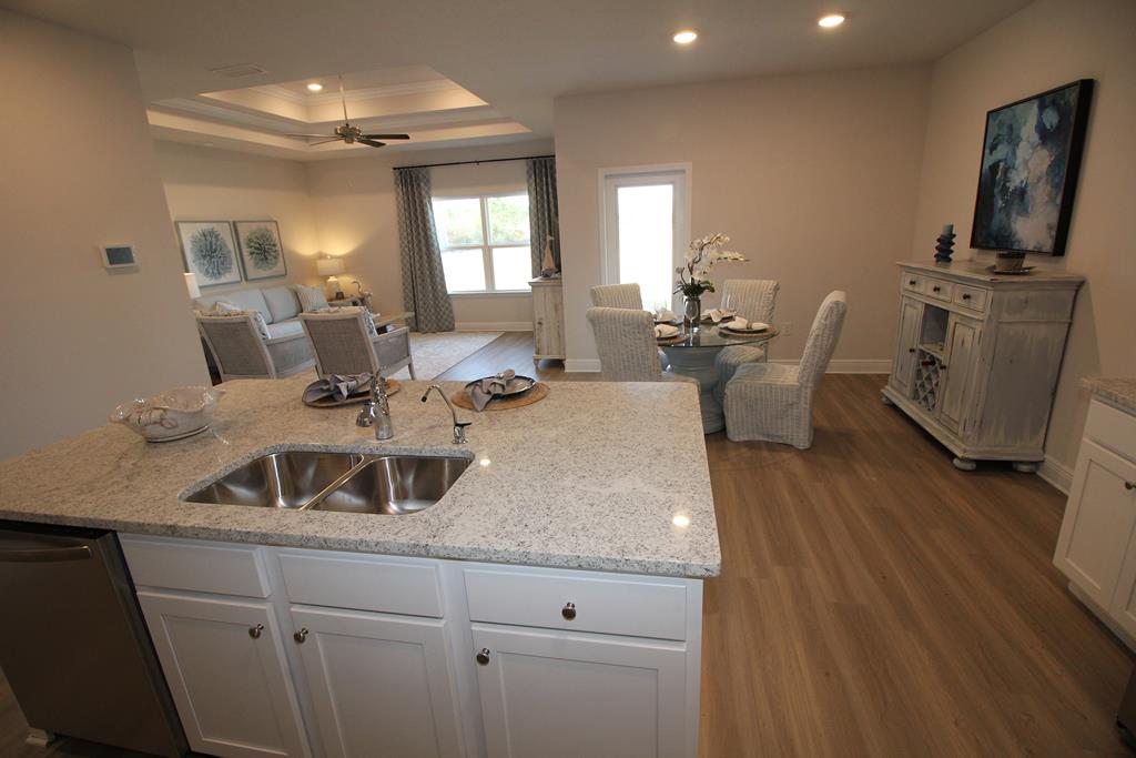Staged kitchen with granite island and sink opens to dining and living areas.