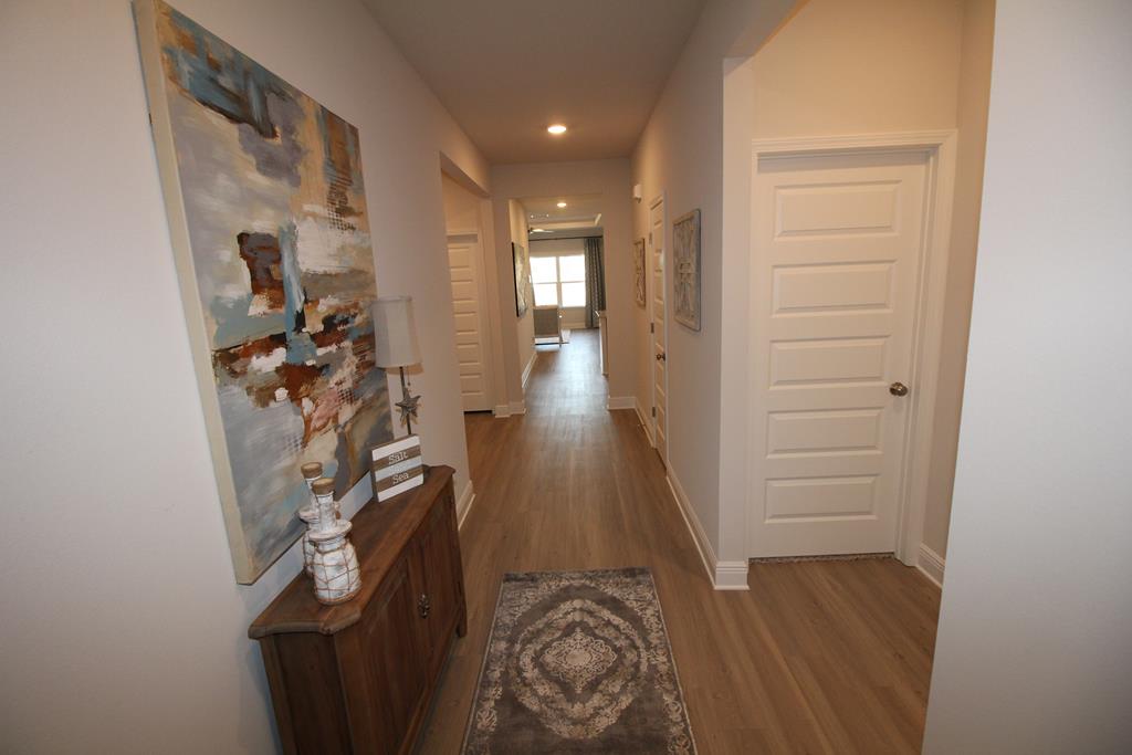 Furnished hallway with wood floors, a patterned runner, and a wooden console beneath abstract art.