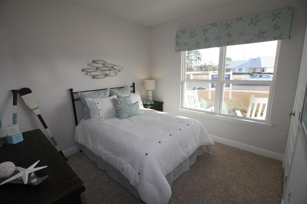 Bedroom with a white bed, aqua accents, and a starfish-patterned window valance.