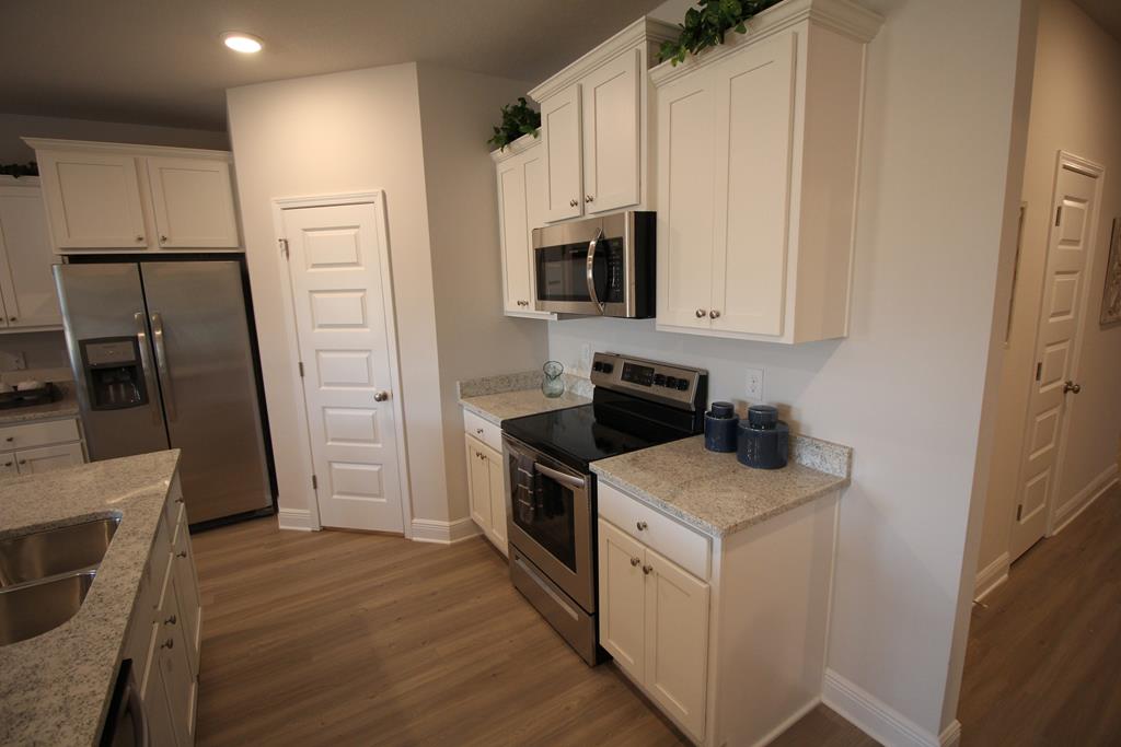 Kitchen with white cabinets, granite counters, and stainless steel appliances.