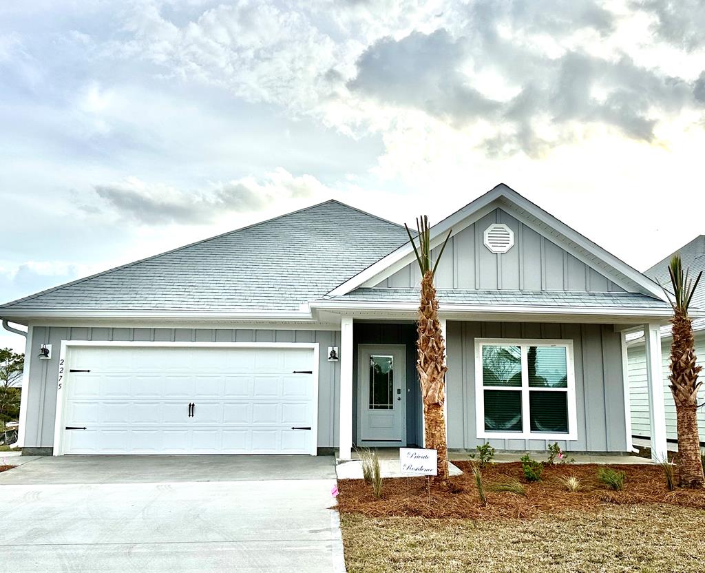 Gray single-story home with a white double garage, covered entry, and palm trees.
