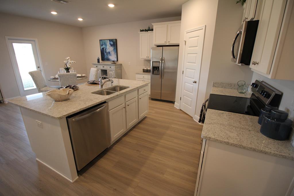 Kitchen with a granite island and stainless steel appliances, opening onto a dining area.